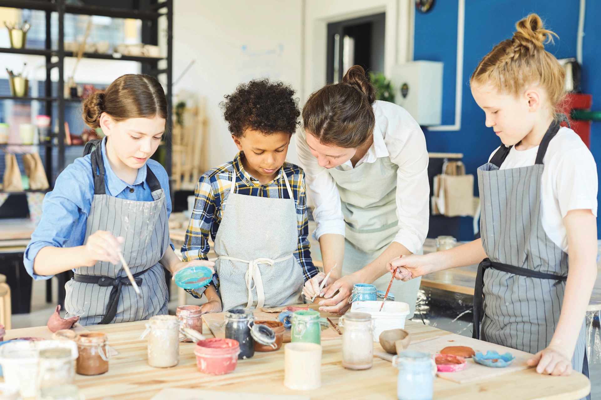 Lehrkraft begleitet drei Schüler beim kreativen Arbeiten – persönlich, nah, engagiert